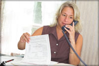mujer hablando por teléfono y revisando documentos
